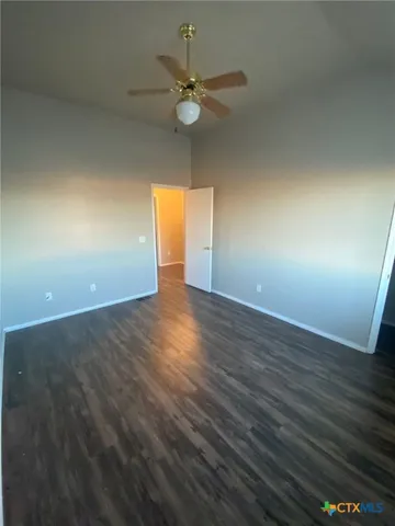 an empty room with wooden floor and fan