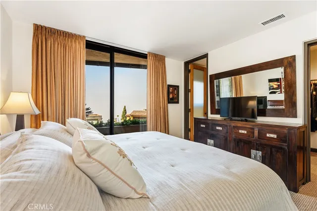 a bedroom with a large bed and a flat tv screen on dresser