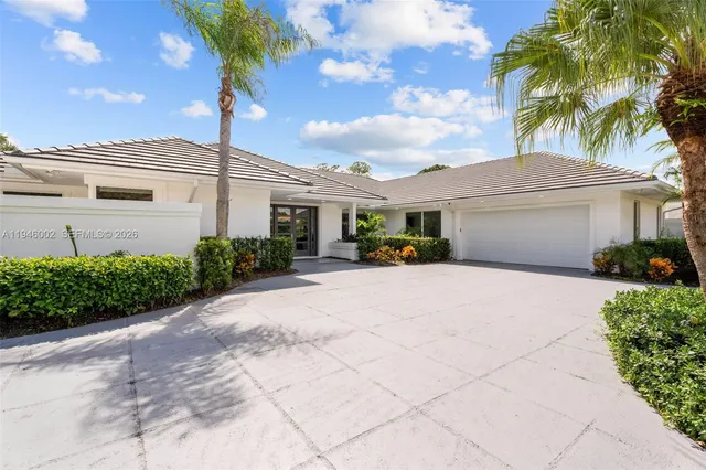 a front view of a house with a garden and palm trees