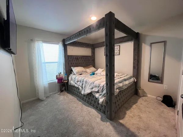 a bedroom with a bed and a flat tv screen on the dresser