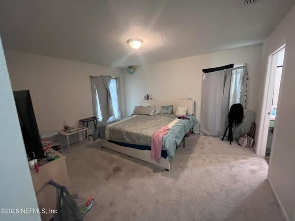 a bedroom with a bed a flat screen tv and windows