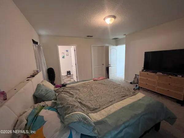 a bedroom with a bed and a flat tv screen on wall