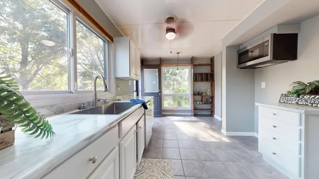a large white kitchen with a large window and stainless steel appliances