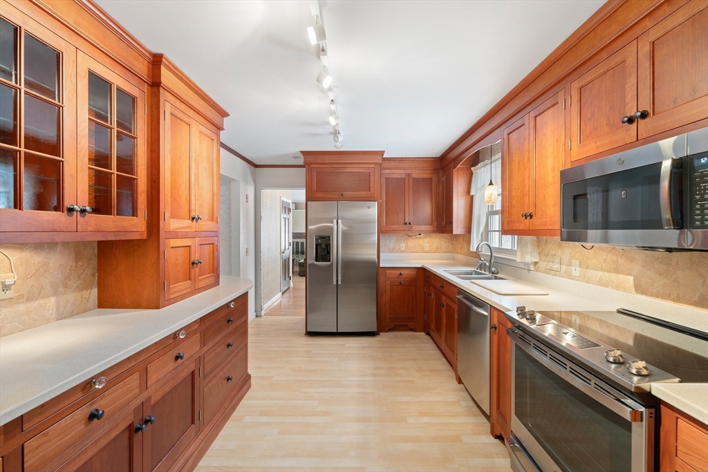 a large kitchen with stainless steel appliances granite countertop a large stove top oven a refrigerator a sink and dishwasher with wooden floor