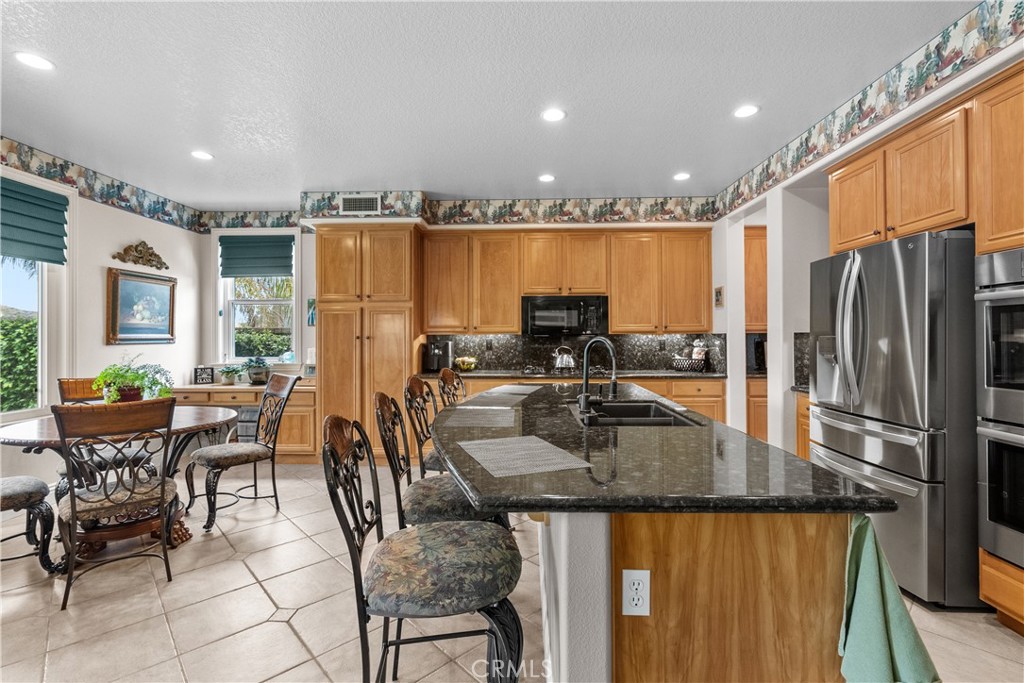 28834 Rock Canyon Drive Saugus, CA 91390 - Photo 16 of 58 a kitchen with granite countertop a refrigerator a stove a sink and chairs