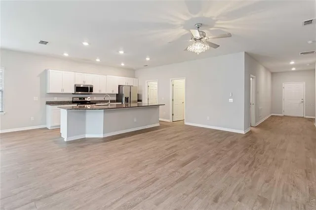 a view of kitchen with kitchen island granite countertop a stove top oven a sink and dishwasher with wooden floor