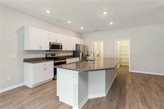 a kitchen with stainless steel appliances granite countertop a sink stove and microwave