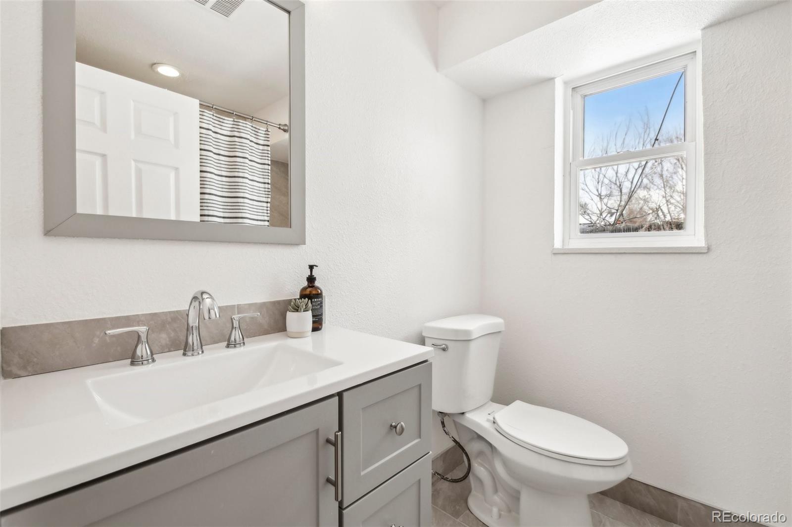 5153 Tucson Way Denver, CO 80239 - Photo 22 of 29 a bathroom with a toilet sink and mirror