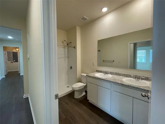 a bathroom with a granite countertop sink a toilet and shower