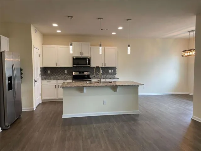 a view of kitchen with stainless steel appliances granite countertop a stove a sink and a refrigerator