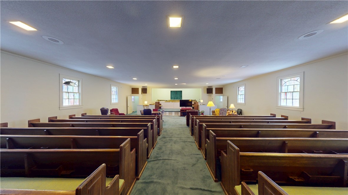 415 Church Street Pendleton, SC 29670 - Photo 15 of 35 A quiet assembly room features classic wooden pews and luminous windows, creating a serene atmosphere for gatherings.