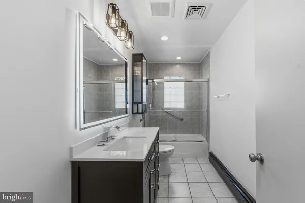 a bathroom with a sink a toilet a mirror and shower