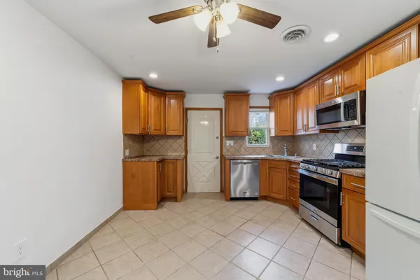 a kitchen with stainless steel appliances granite countertop a refrigerator a sink dishwasher a stove with wooden cabinets