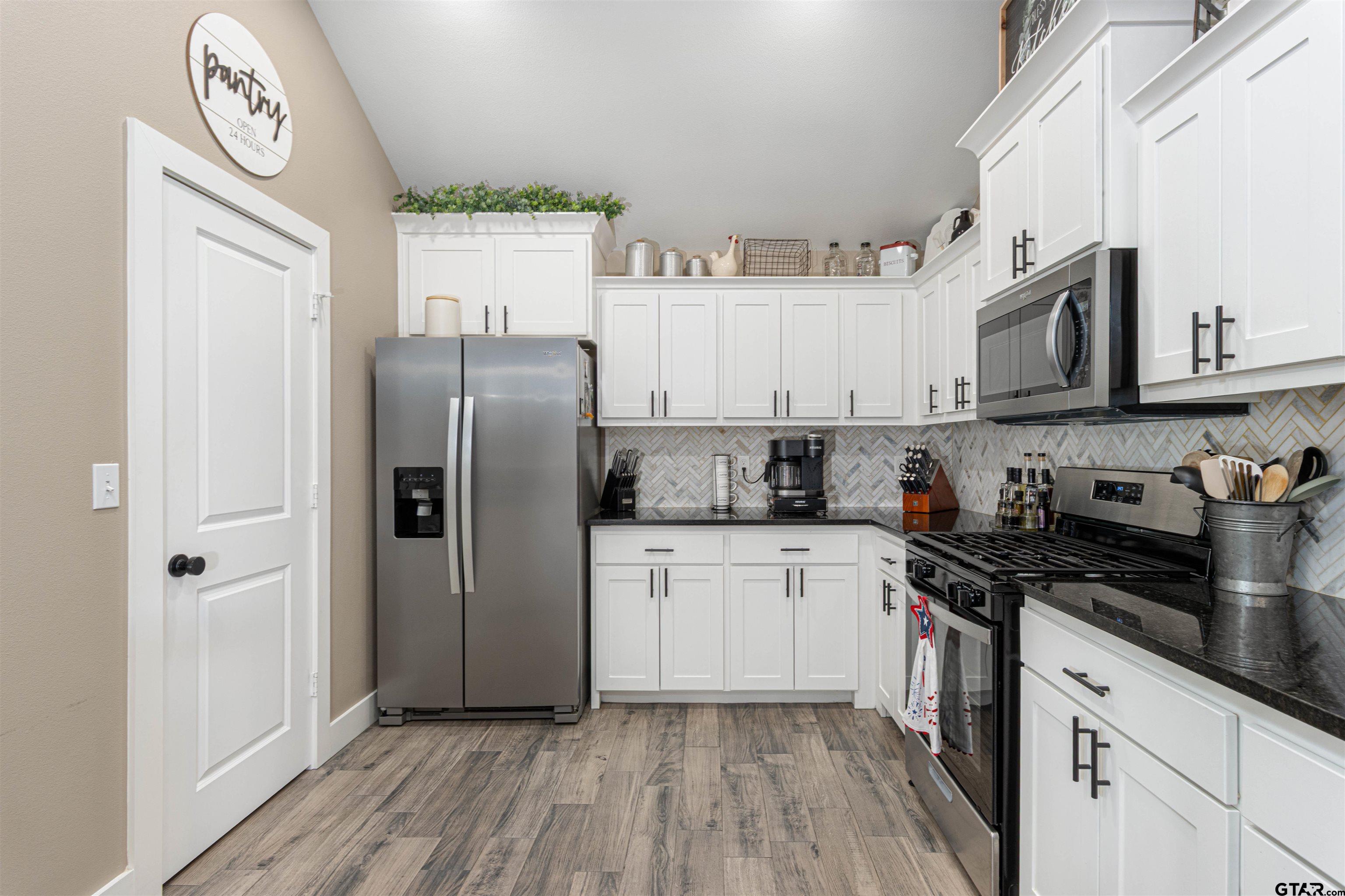 16210 Crossing Circle Lindale, TX 75771 - Photo 4 of 22 a kitchen with stainless steel appliances granite countertop a refrigerator a sink and white cabinets with wooden floor
