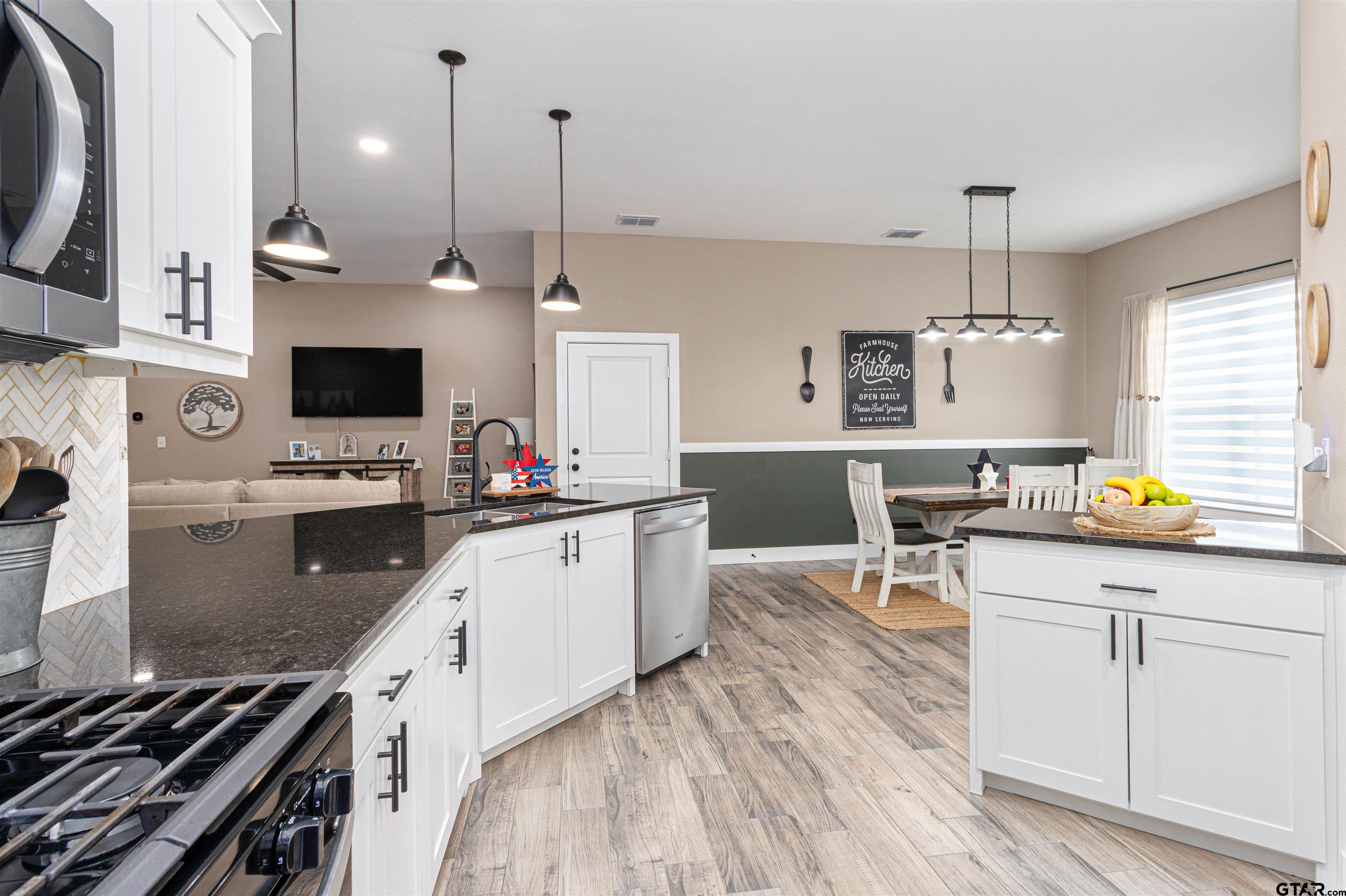 16210 Crossing Circle Lindale, TX 75771 - Photo 6 of 22 a kitchen with stainless steel appliances a stove top oven a sink dishwasher and a dining table with wooden floor