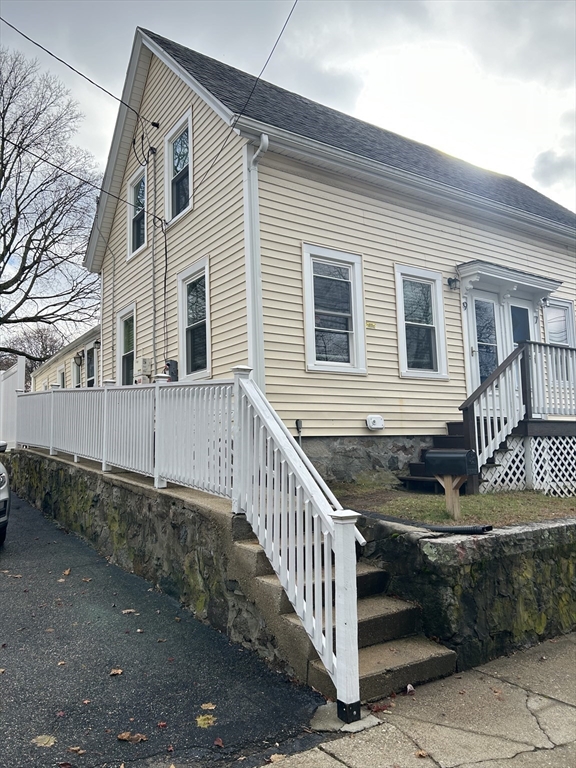 a front view of a house with stairs and wooden fence