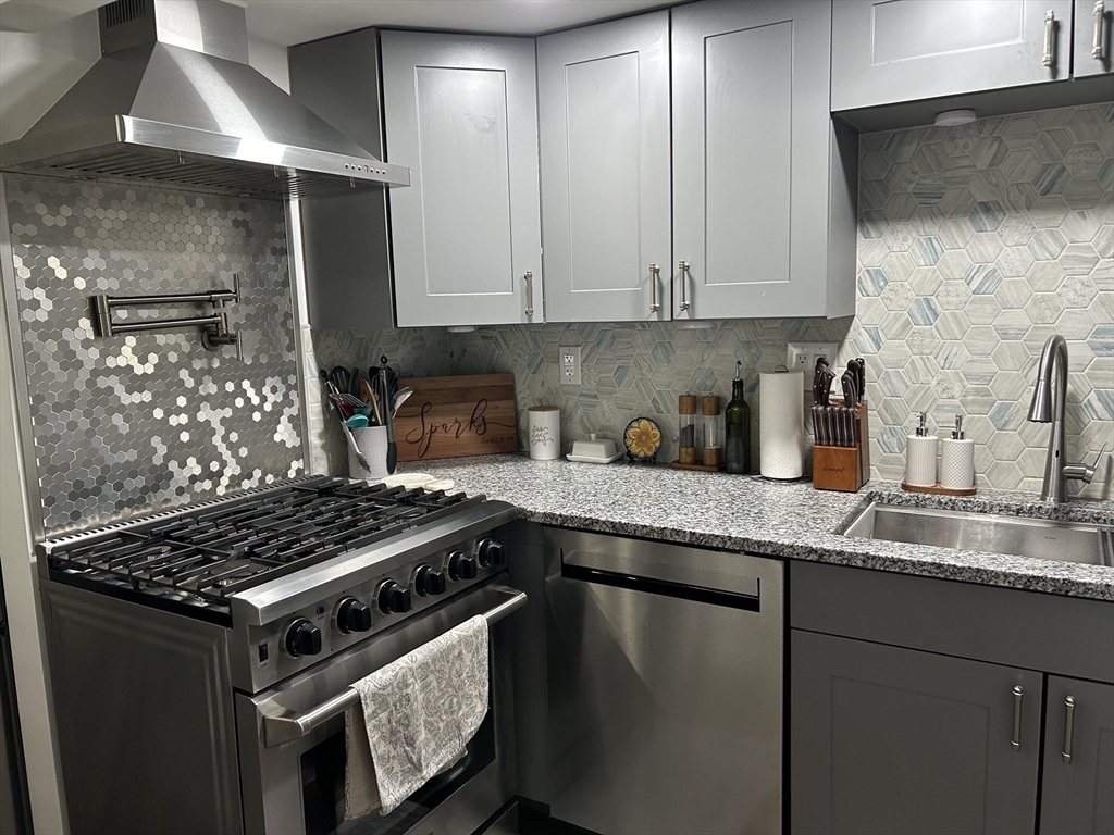9 Church Street, Unit 9 Woburn, MA 01801 - Photo 5 of 31 a kitchen with granite countertop stainless steel appliances a sink stove and cabinets
