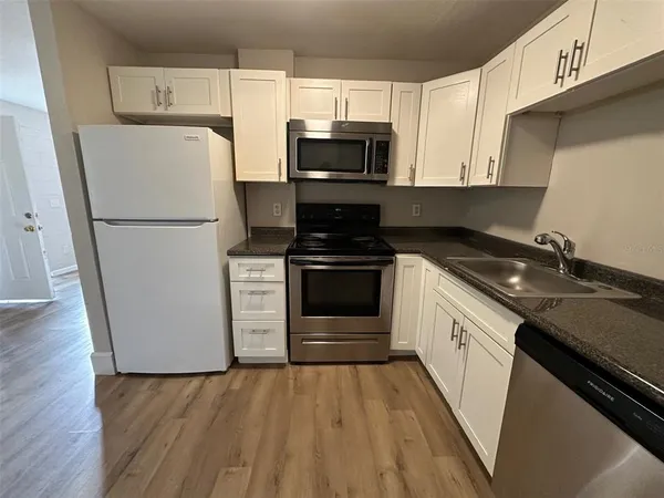 a kitchen with a sink a microwave a refrigerator and cabinets