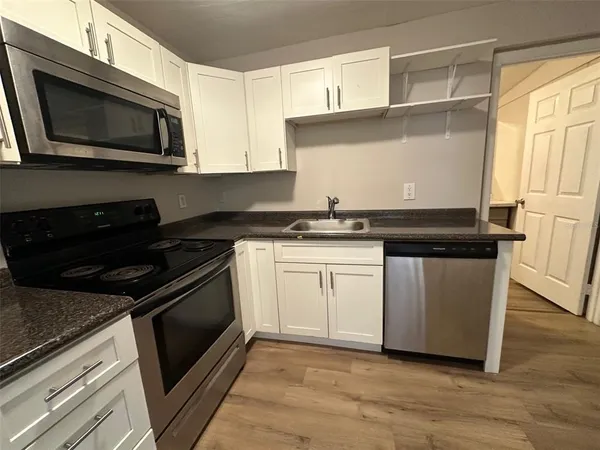 a kitchen with granite countertop white cabinets and black appliances