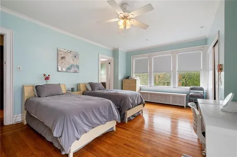 a bedroom with a bed couches and a large window with wooden floor