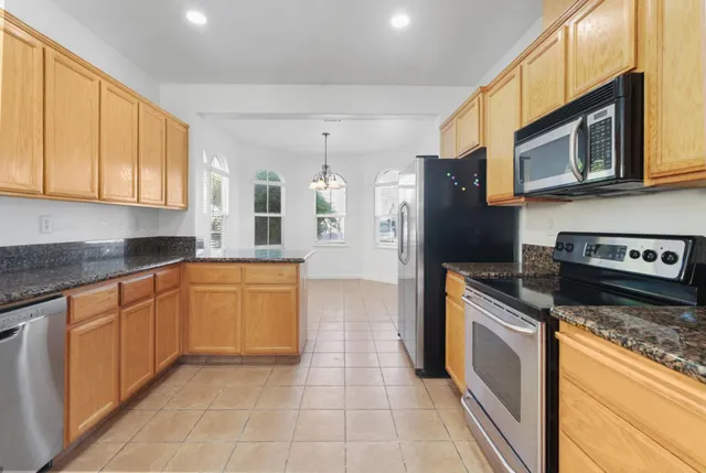 a large kitchen with stainless steel appliances granite countertop a stove a sink and a microwave