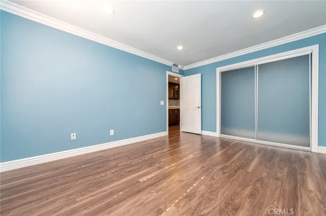 a view of an empty room with wooden floor and closet