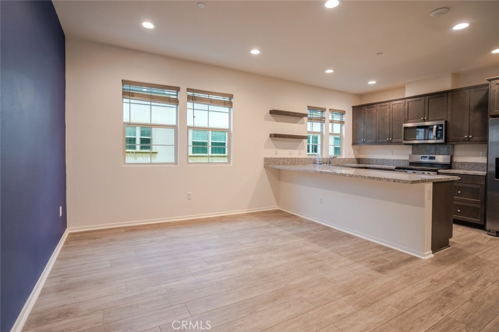 863 Iris Way, Unit B Azusa, CA 91702 - Photo 7 of 29 a large kitchen with stainless steel appliances granite countertop a stove a sink a refrigerator white cabinets and a wooden floor