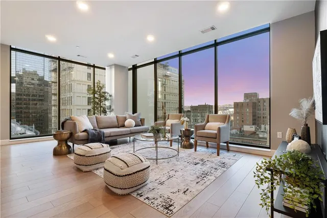 a living room with furniture a large window and wooden floor