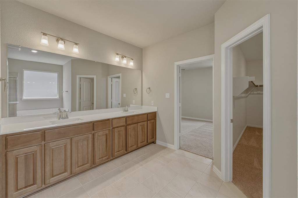 1209 Colca Drive Springtown, TX 76082 - Photo 16 of 24 Double vanity with light wood-finish cabinetry, white countertops, and dual undermount sinks