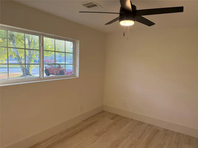 a view of empty room with wooden floor and fan