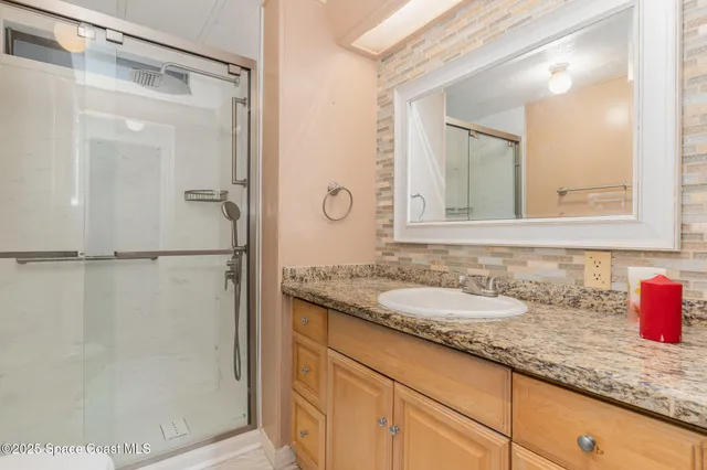 a bathroom with a granite countertop shower sink and mirror