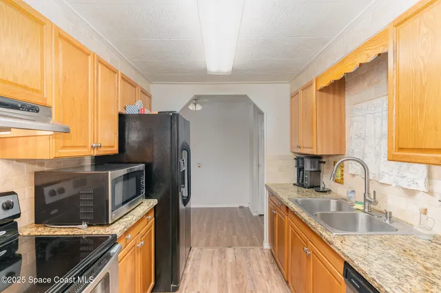 a kitchen with granite countertop a refrigerator stove and sink