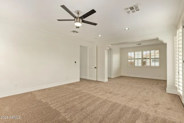 an empty room with windows and ceiling fan