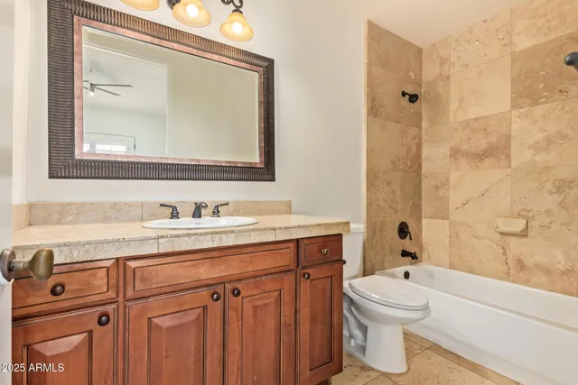 a bathroom with a granite countertop toilet sink and mirror