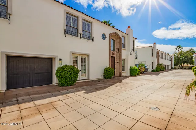 a view of a white house with a small yard and large tree
