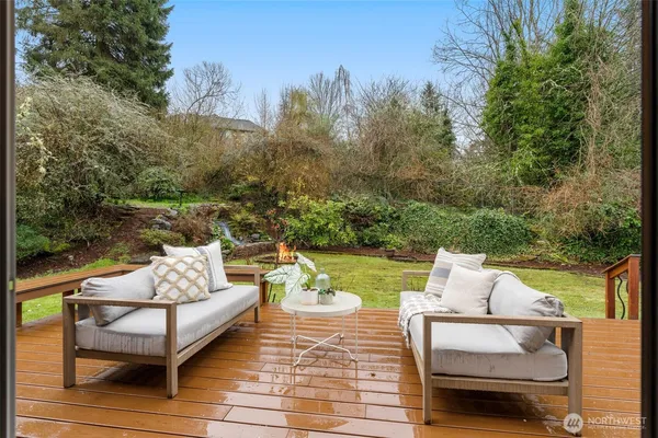a view of a patio with couches table and chairs under an umbrella with large trees