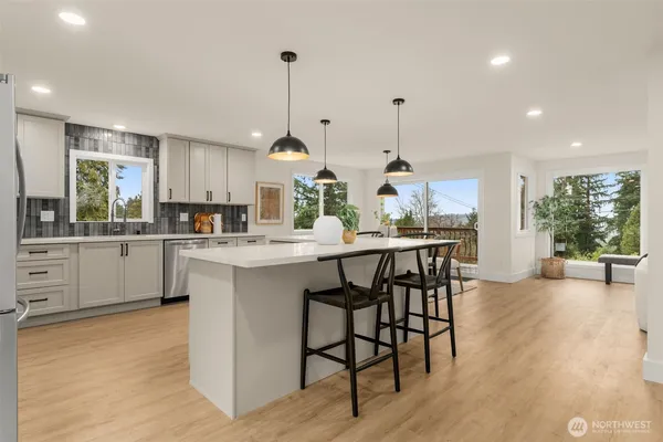 a kitchen with stainless steel appliances kitchen island granite countertop a table chairs sink and cabinets