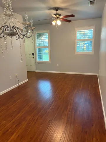 a view of empty room with wooden floor and fan