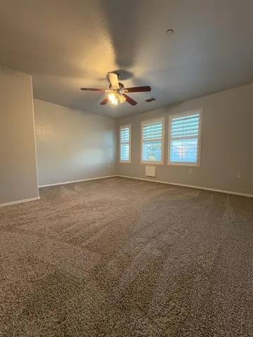 en empty room with windows and ceiling fan
