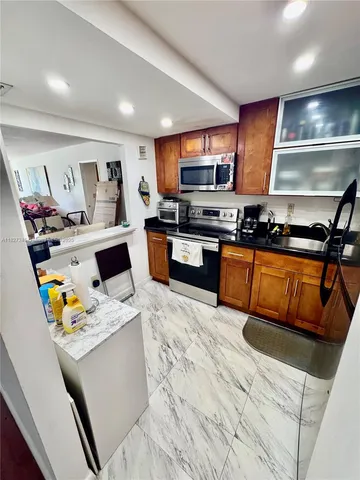 a kitchen with stainless steel appliances granite countertop a sink dishwasher stove top oven and cabinets with wooden floor