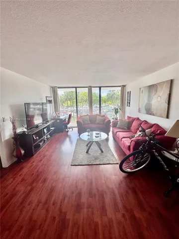 a living room with furniture large window and a wooden floor