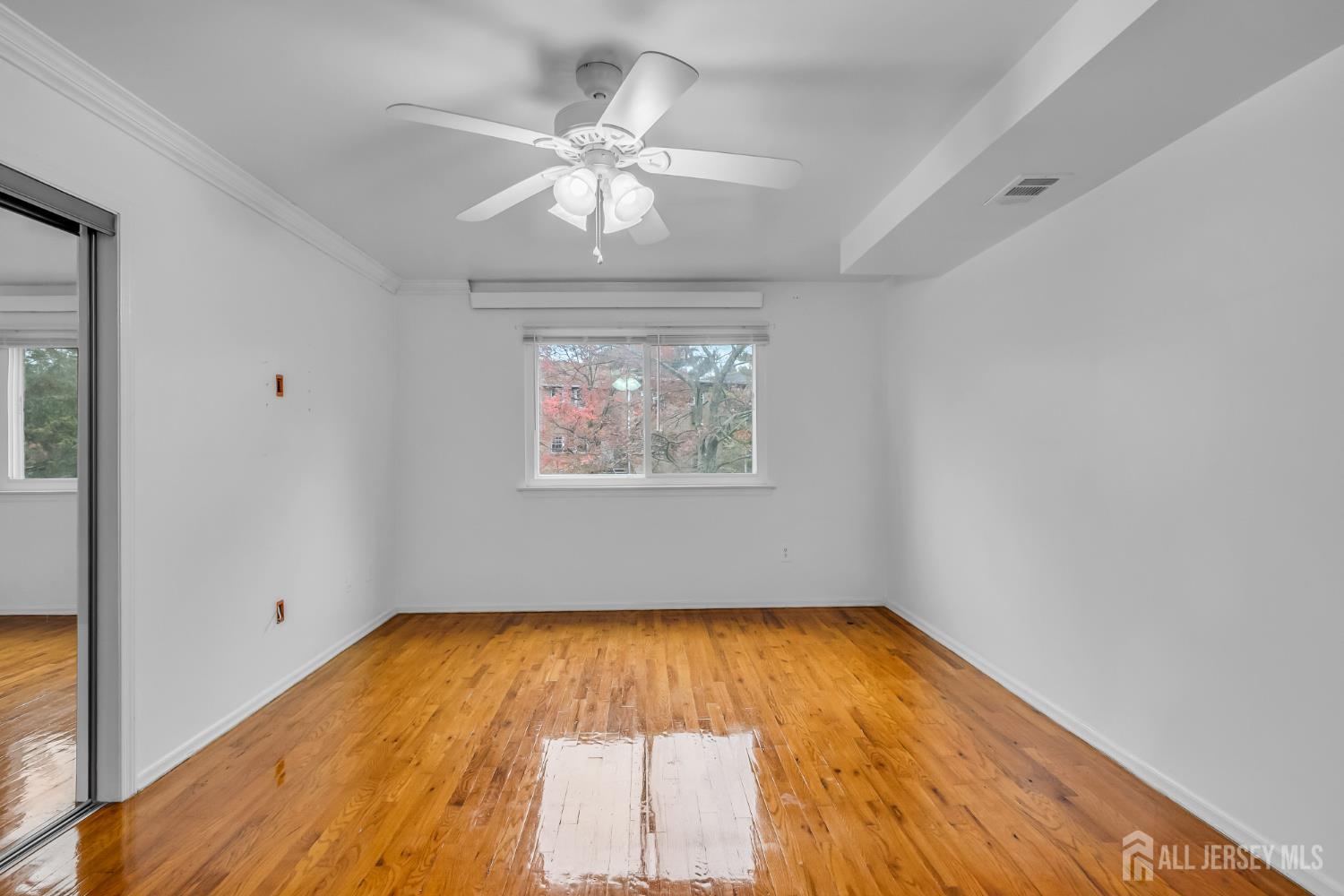 14 College Drive Edison, NJ 08817 - Photo 13 of 22 an empty room with wooden floor chandelier fan and windows