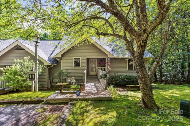a backyard of a house with yard plants and large tree