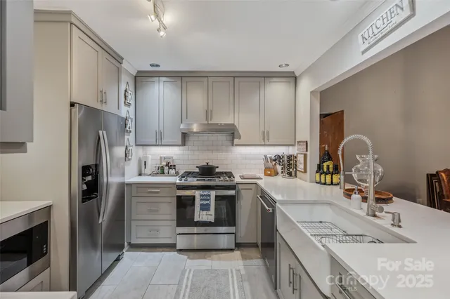 a kitchen with stainless steel appliances granite countertop a sink stove refrigerator and cabinets