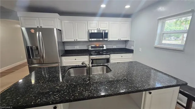 a kitchen with stainless steel appliances granite countertop a sink a stove and a refrigerator