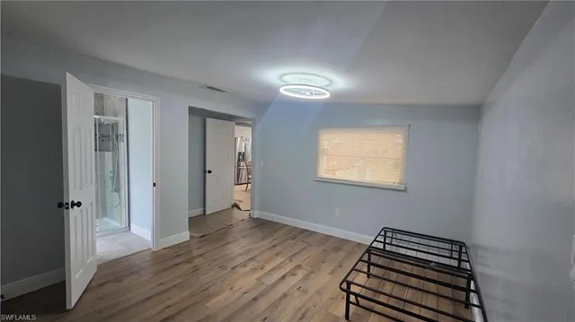 an empty room with wooden floor closet and windows