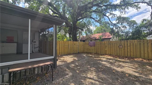 a view of a backyard with large trees and wooden fence