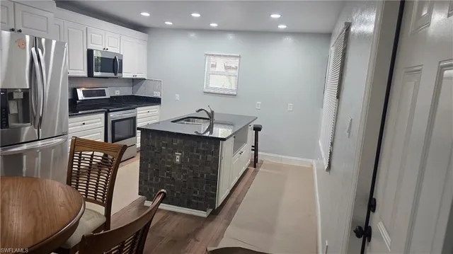 a kitchen with stainless steel appliances granite countertop a refrigerator a stove a sink a dining table and chairs