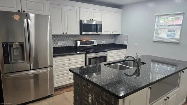 a kitchen with stainless steel appliances granite countertop a sink a microwave and refrigerator