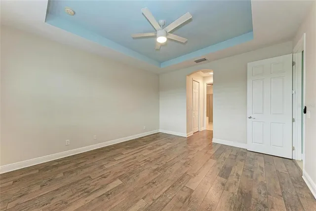 an empty room with wooden floor and ceiling fan